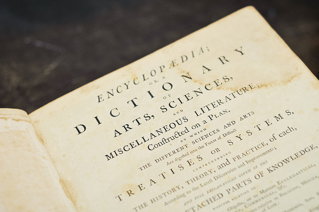 Close-up of an antiqued page corner within a dictionary laying on a dark gray table